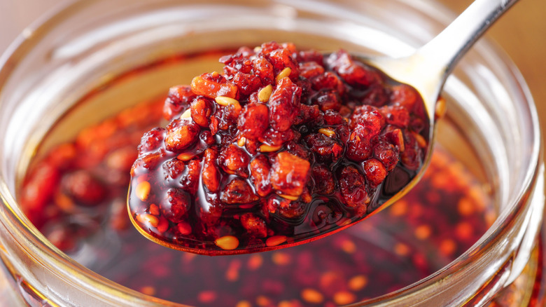 Spooning chili crisp from a glass jar