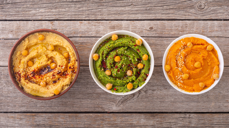 Overhead view of three bowls of hummus in various flavors