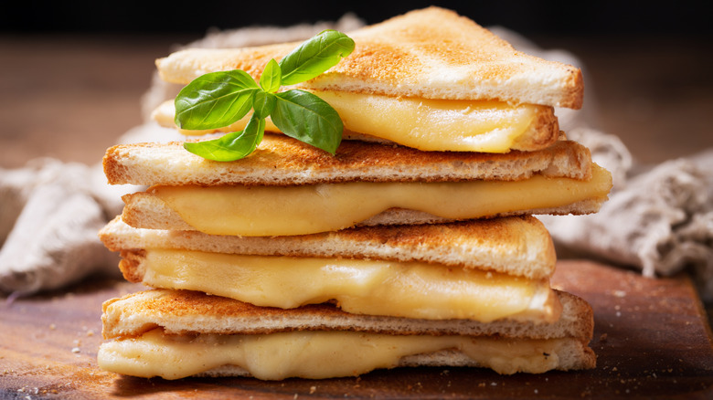 Stack of grilled cheese sandwiches on a cutting board