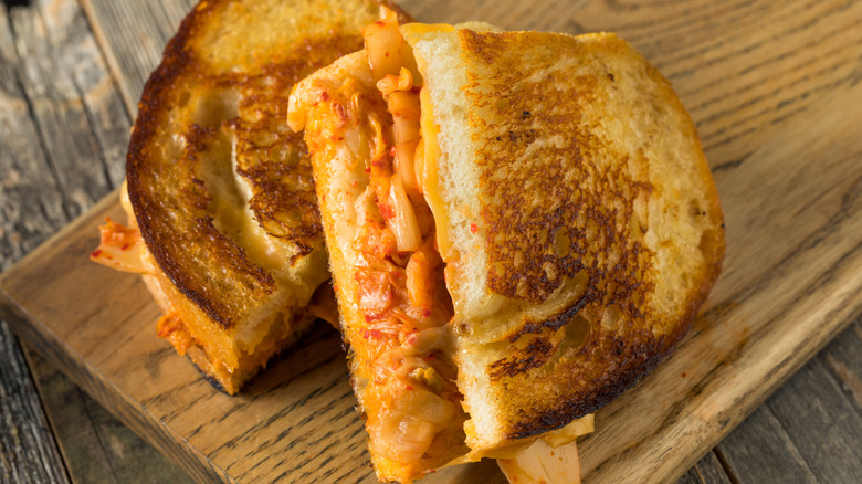 A grilled cheese sandwich with kimchi on a cutting board
