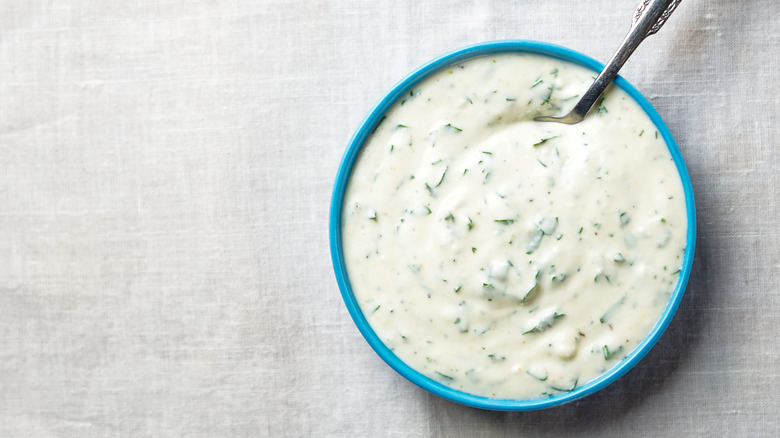Overhead view of a blue bowl full of ranch dressing with a spoon