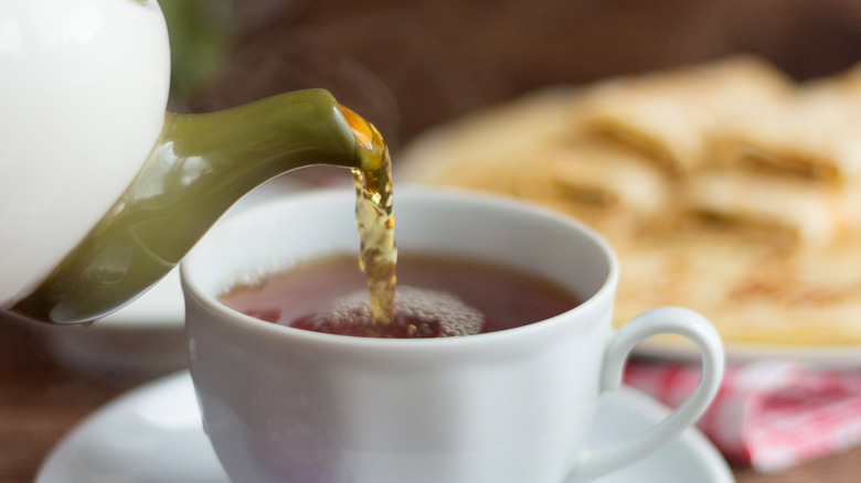 Pouring English breakfast tea into white teacup