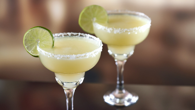 Two margaritas with salted rims and lime slices