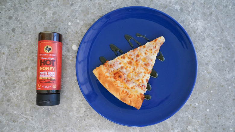 Desert Creek hot honey bottle with pizza and hot honey drizzle on blue plate
