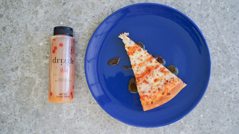 Drizzle hot honey bottle with pizza and hot honey drizzle on blue plate