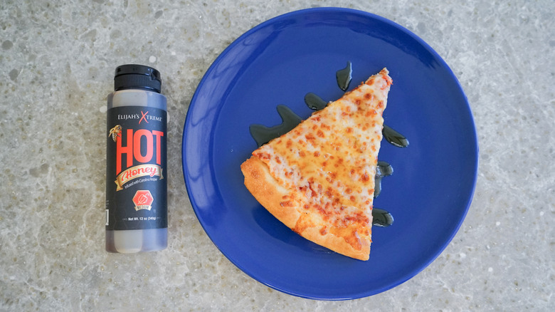 Elijah's Xtreme hot honey bottle with pizza and hot honey drizzle on blue plate