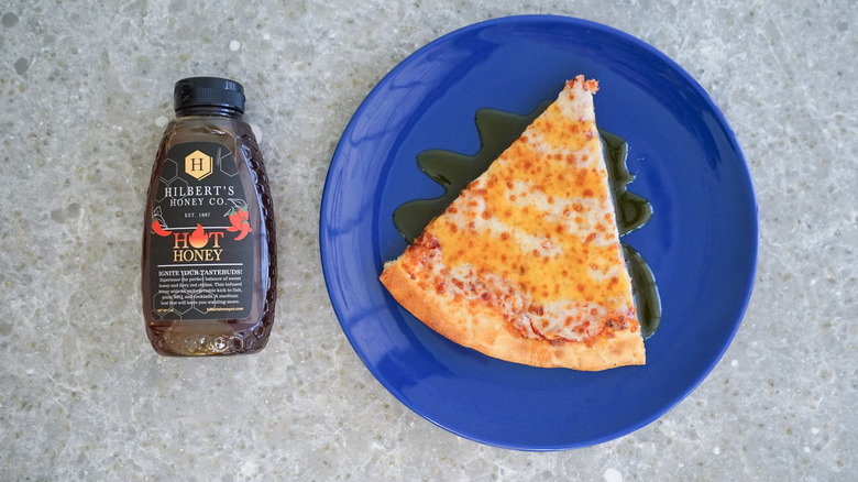 Hilbert's hot honey bottle with pizza and hot honey drizzle on blue plate