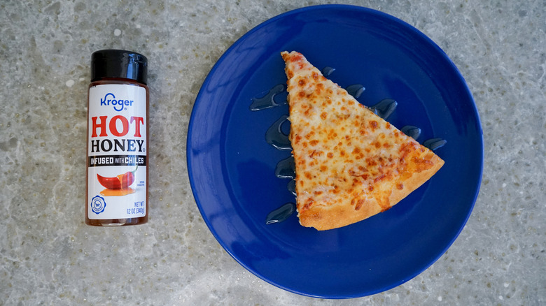 Kroger hot honey bottle with pizza and hot honey drizzle on blue plate
