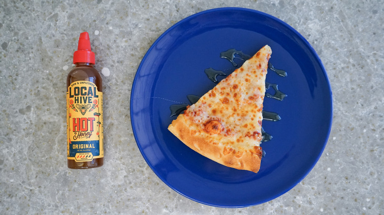 Local Hive hot honey bottle with pizza and hot honey drizzle on blue plate