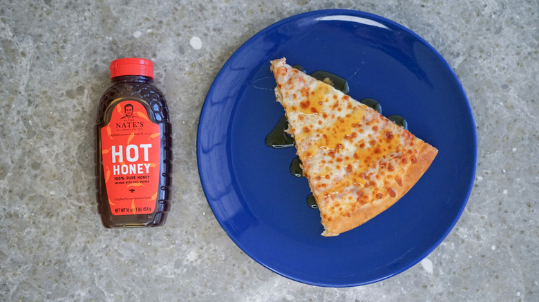 Nature Nate's hot honey bottle with pizza and hot honey drizzle on blue plate