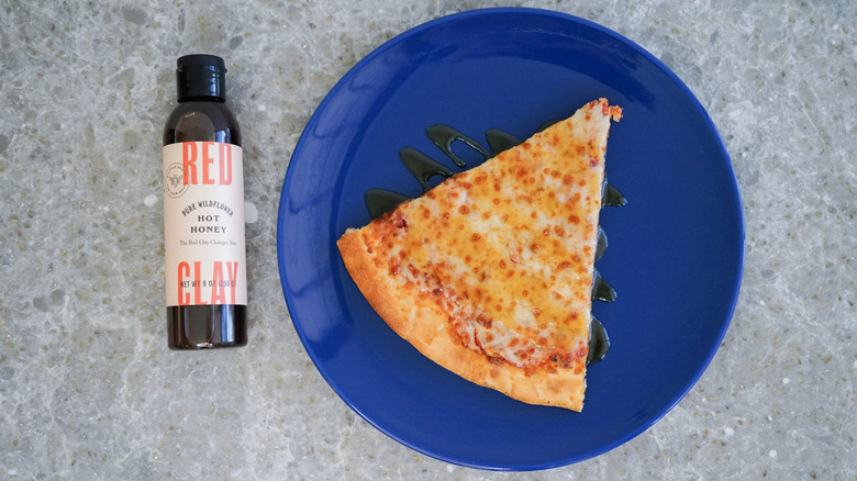 Red Clay hot honey bottle with pizza and hot honey drizzle on blue plate