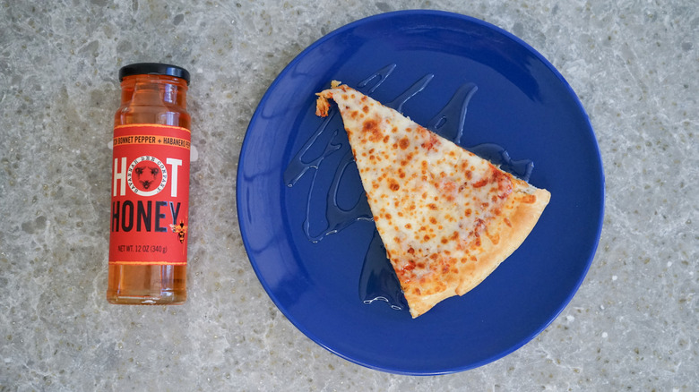 Savannah Bee hot honey bottle with pizza and hot honey drizzle on blue plate