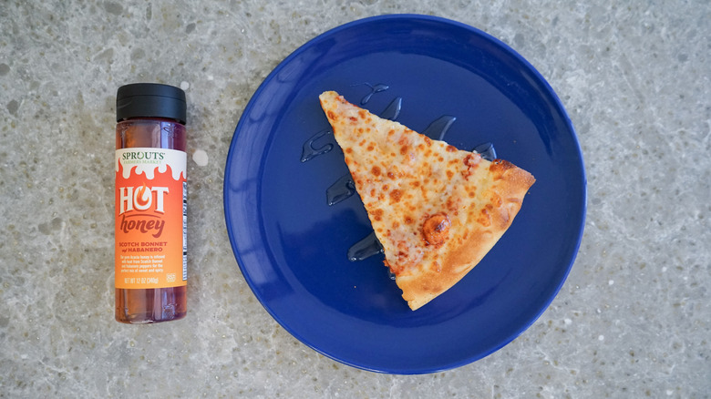 Sprouts hot honey bottle with pizza and hot honey drizzle on blue plate