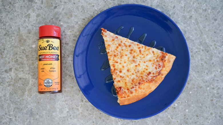 Sue Bee hot honey bottle with pizza and hot honey drizzle on blue plate