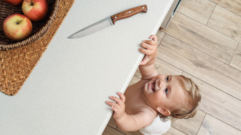 Baby reaching toward knife on kitchen counter