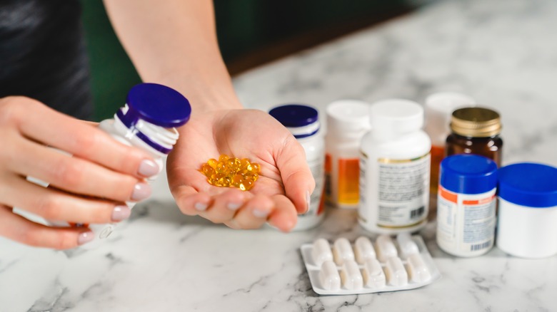 Person putting vitamins in hand in kitchen