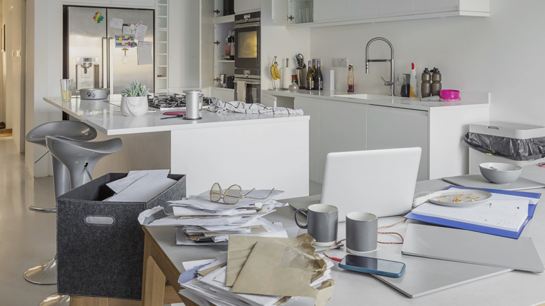 Kitchen filled with papers, computers, and other items