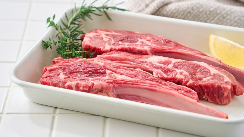 Raw lamb chops on kitchen counter in white tray