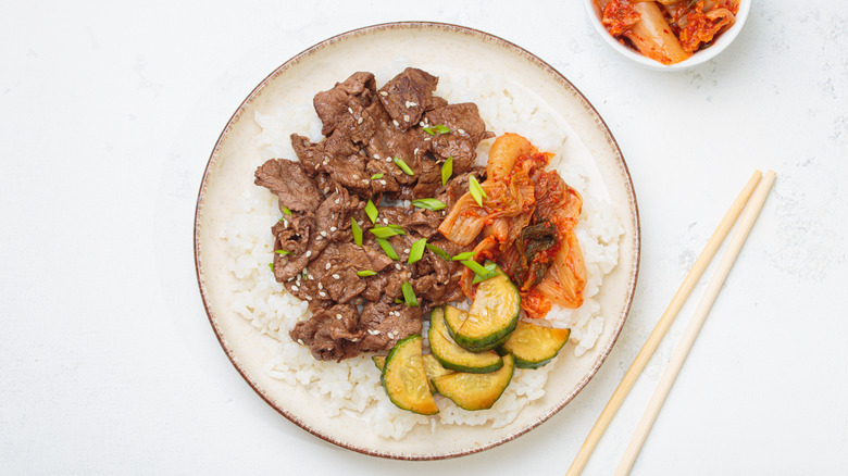 Plate of bulgogi with rice, kimchi, and cucumbers