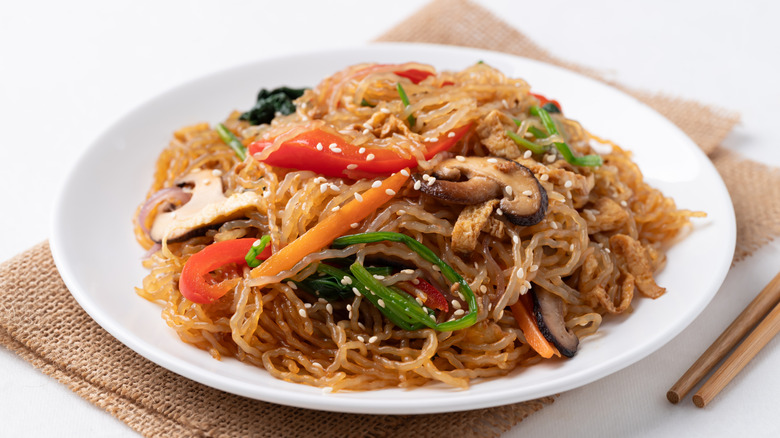 Vegetable japchae on white plate with chopsticks