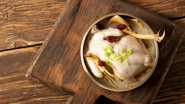 A bowl of samgyetang on a wooden cutting board