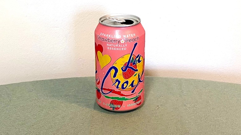 a pink can of strawberry peach La Croix sits on a table