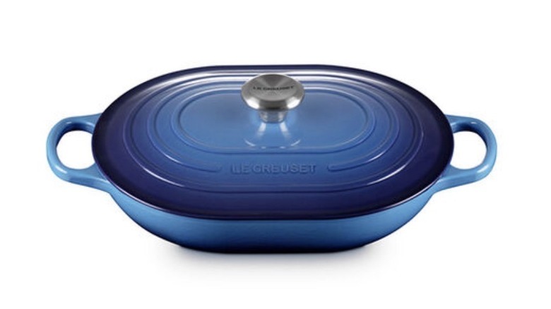 A high-angled image of a blue Le Creuset oval casserole dish with a lid