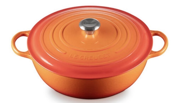 An orange soup pot with handles on both sides and a lid