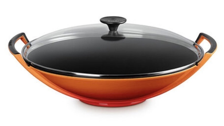 A sophisticated orange wok from Le Creuset with a glass lid