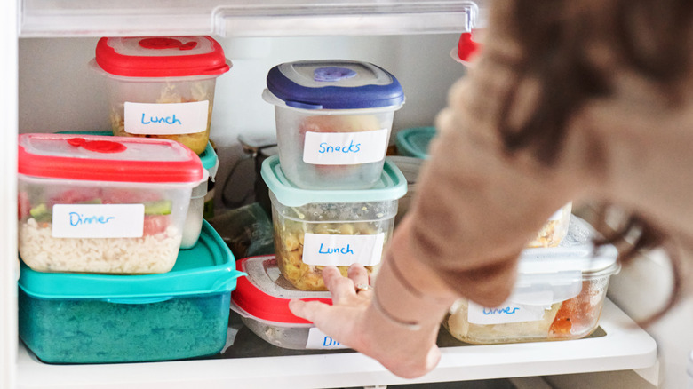 person leaning into fridge looking at leftovers