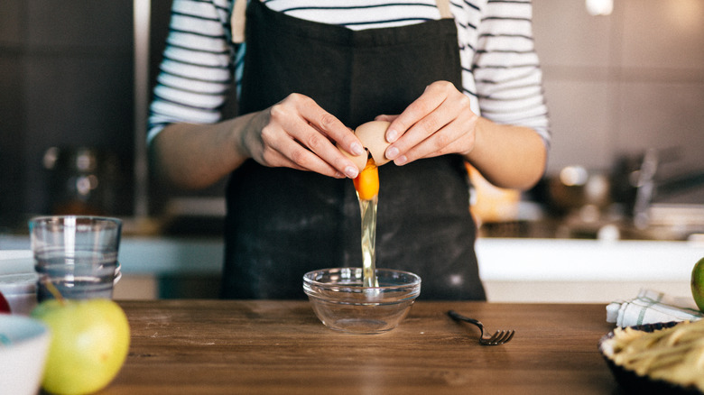 person cracking egg into bowl
