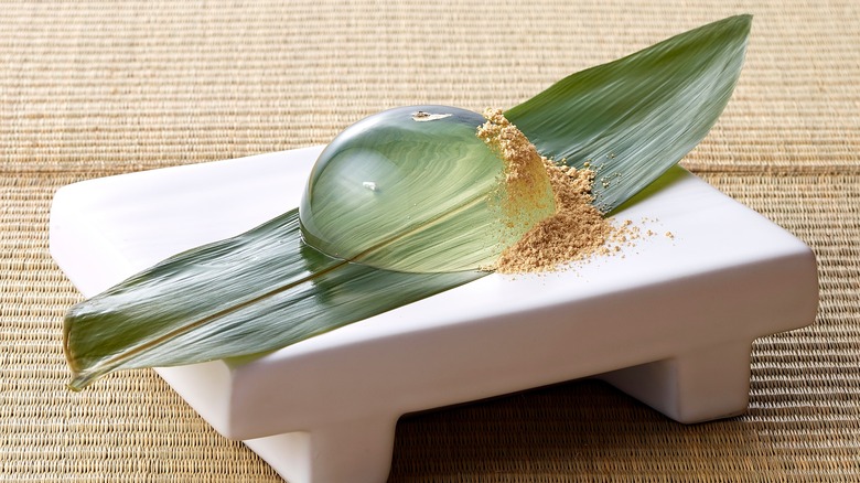 Raindrop cake sitting on a leaf which is dressed on a platter