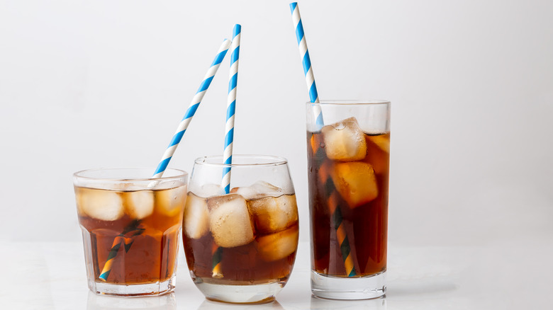 Three differently-sized cups of Coke with blue and white striped straws