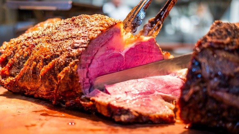 A person slicing a prime rib roast on a cutting board at Bartlett's
