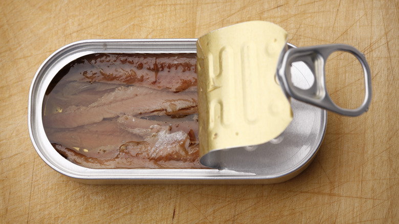 open can of anchovies on wood table