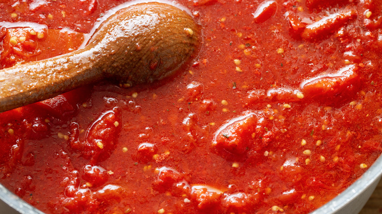 tomato sauce in silver pot with wooden spoon