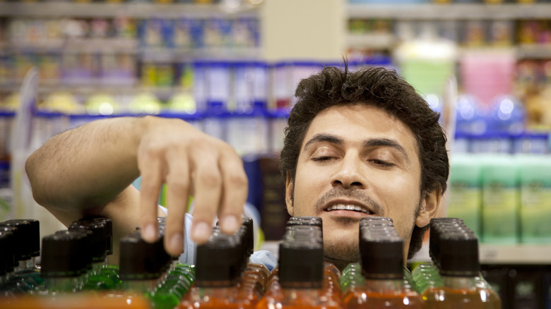 Man reaching for a bottle at the back of the shelf from the perspective of the shelf