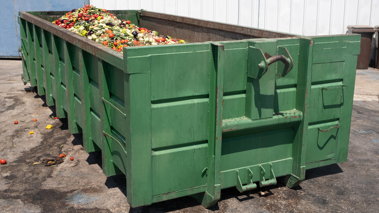 A green dumpster nearly full of wasted produce