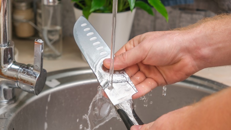 Person washing knife with water