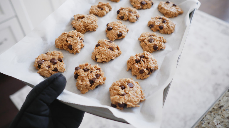Person holding tray lined with parchment paper and cookies