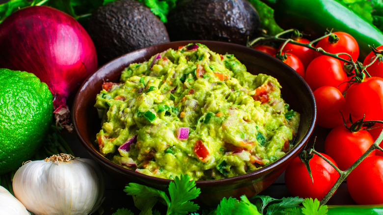 Bowl of guacamole in the center of fresh vegetables.