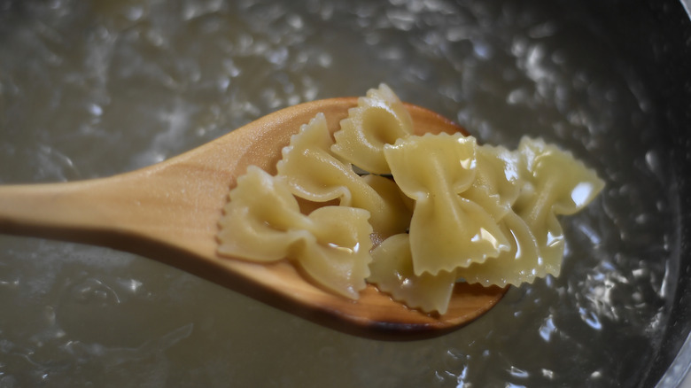 Partially cooked farfalle noodles in a wooden spoon