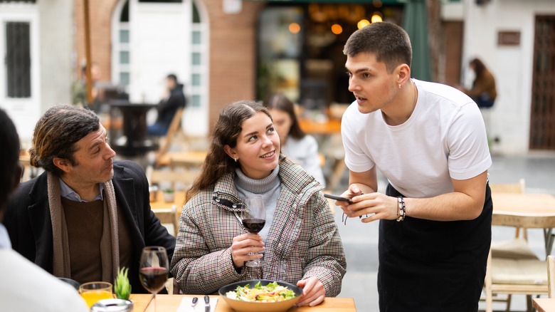 server holding phone looking confused