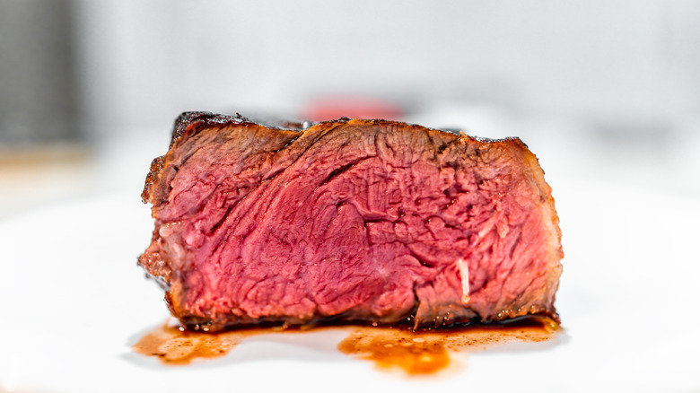 medium-rare steak sitting on white plate