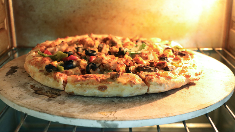 Pizza stone in an oven with a pizza