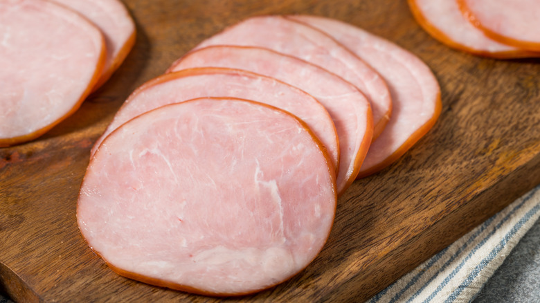 slices of Canadian bacon on a wooden cutting board