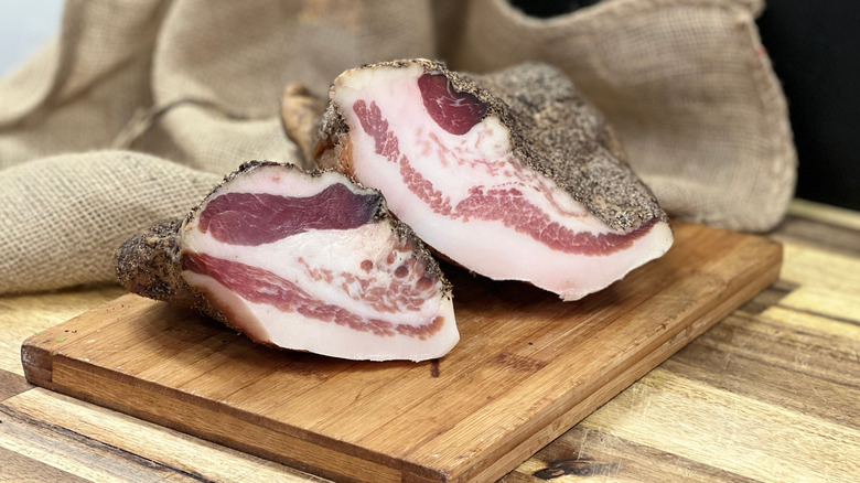 two pieces of Italian guanciale on a cutting board