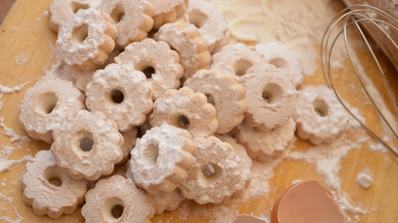 A pile of canestrelli cookies on a floured baking surface