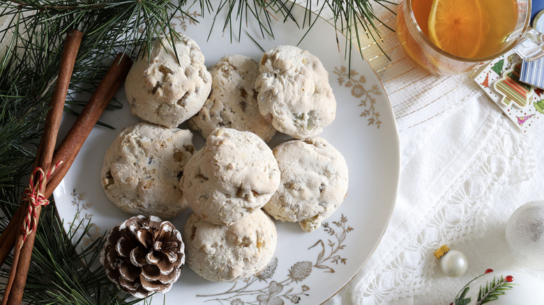 A plate of cavallucci cookies next to a pinecone and other holiday decor
