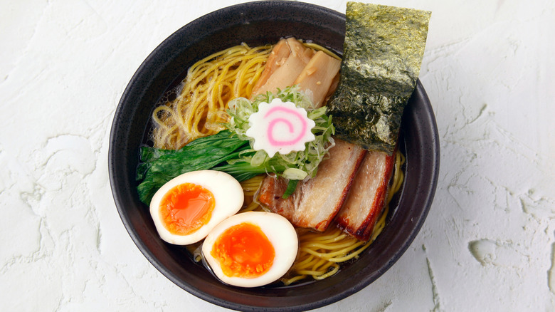 A bowl of chintan ramen topped with eggs, pork, and various veggies in a black bowl